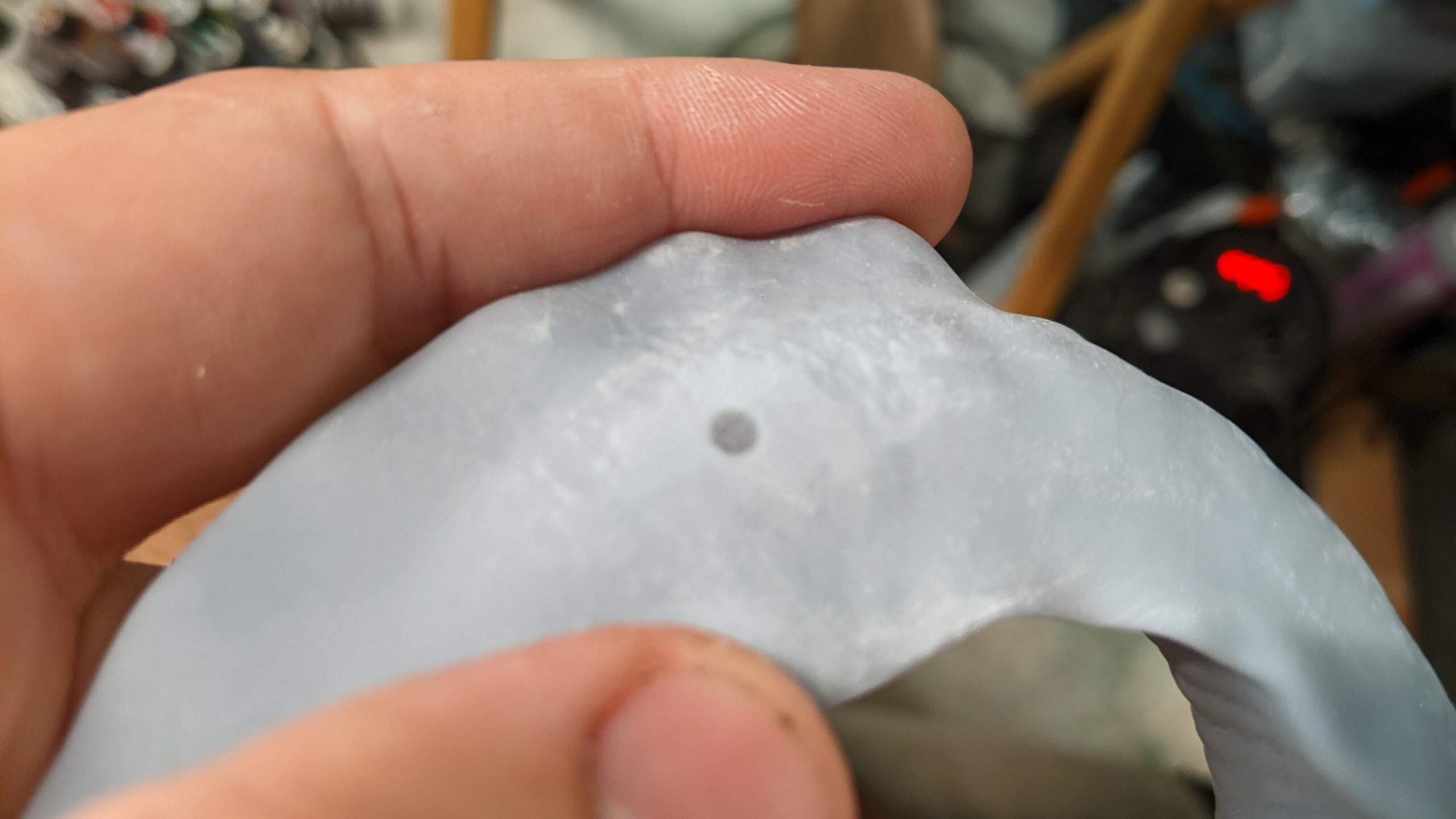 A person holding a gray silicone object with a small dark dot on it.